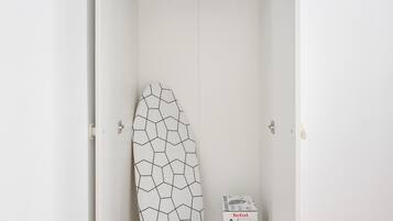 A white wardrobe with a geometric-patterned surfboard and a Tefal appliance on the shelf.