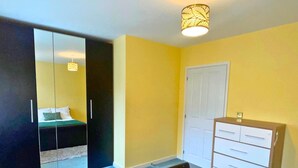 Een slaapkamer met een bed, een kledingkast, een dressoir en een spiegel.
