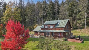 A log cabin with a green metal roof, surrounded by a forest. - Newly Listed! Cabin-style home. (TFH) (Friday Harbor)