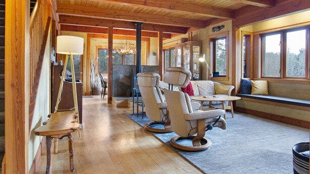 A wooden interior with a stone fireplace, seating area, and large windows. - Newly Listed! Cabin-style home. (TFH) (Friday Harbor)