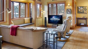 A cozy living room with a large flat-screen TV, wooden beams, a sofa with cushions, and a window seat. - Newly Listed! Cabin-style home. (TFH) (Friday Harbor)