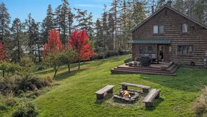 A rustic cabin with a deck, surrounded by a well-maintained lawn and tall trees. - Newly Listed! Cabin-style home. (TFH) (Friday Harbor)