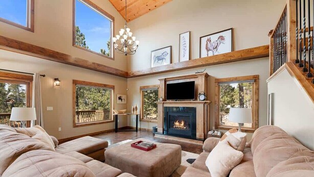 A spacious living room with a fireplace, large windows, and a high ceiling. - Dakota Ridge (Lead)