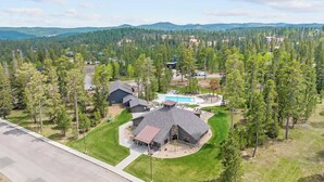 A residential area with a large house featuring a circular driveway, a swimming pool, and a well-maintained lawn. - Dakota Ridge (Lead)