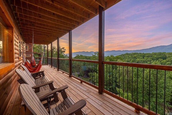 A wooden deck with a view of a forested mountain range.