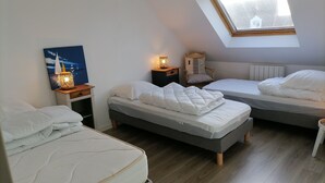 A bedroom with two beds, a skylight, a nightstand with a lamp, and a chair with a cushion. - Maison à la Mer, "Le Petit Léjon", Idéale Familles ou Amis (Plérin)