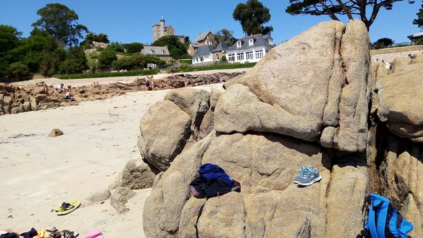 A beach with large rocks, a sandy shore, and a white building with a tower in the background. - Maison à la Mer, "Le Petit Léjon", Idéale Familles ou Amis (Plérin)
