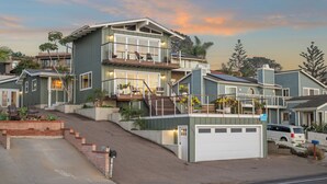 A two-story house with a garage, a covered outdoor seating area, and a driveway leading to a parking space.