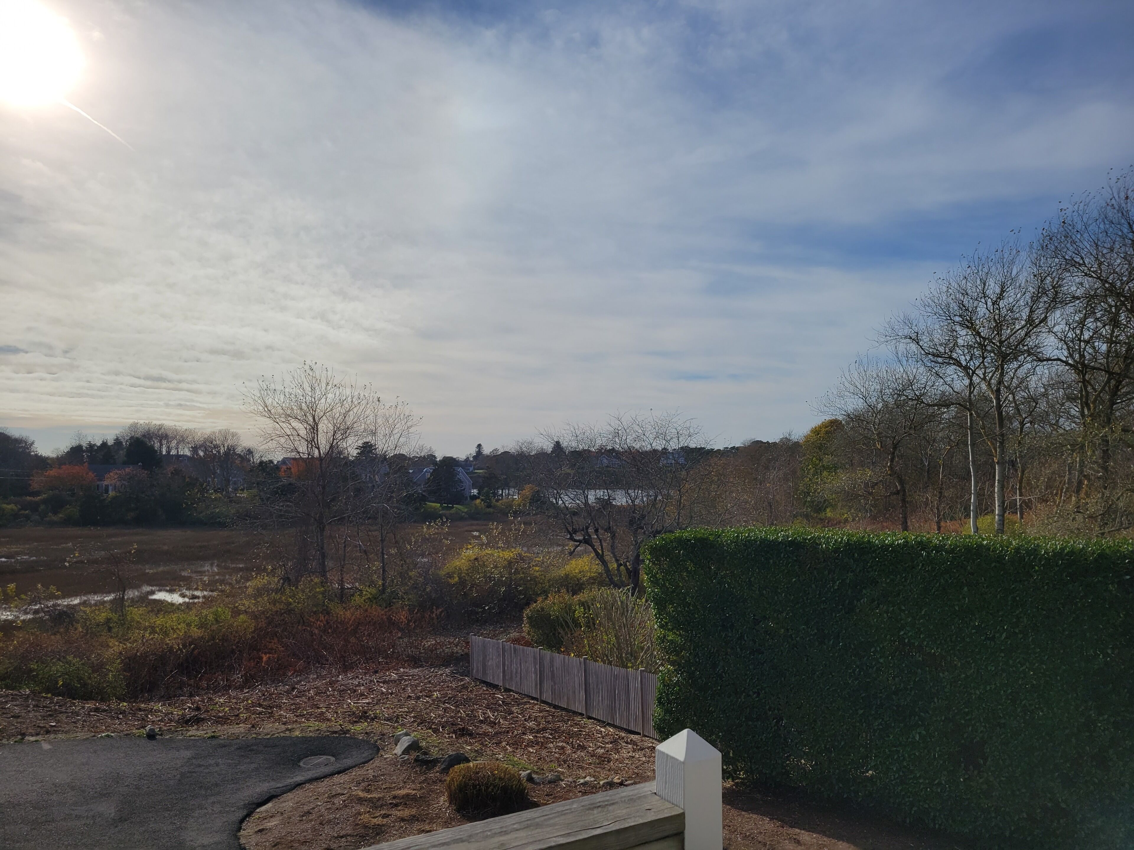 Un quartier résidentiel avec une allée pavée, une clôture en bois et une haie.
