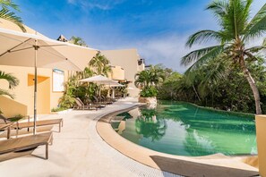 Relax by the pool surrounded by palm trees and lounge chairs.