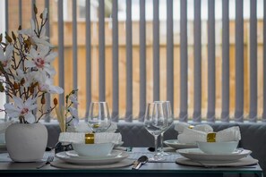 A dining table set with white plates, bowls, and glasses, accompanied by a vase of white flowers. - Riverside Retreat - Luxurious 4 Bedroom House (Stockton-on-Tees)