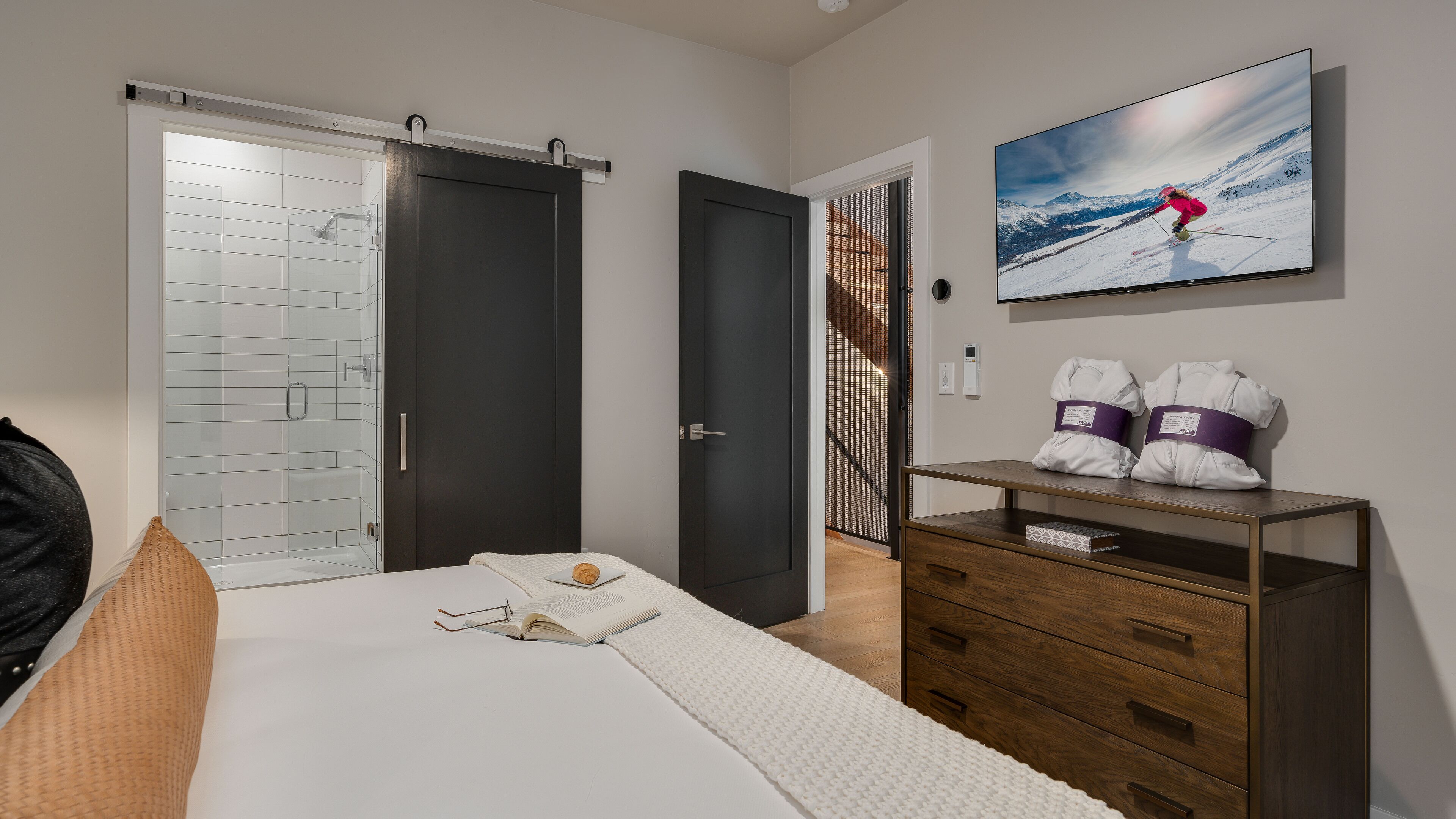 Une chambre à coucher avec un lit, une commode, un téléviseur et une porte coulissante.