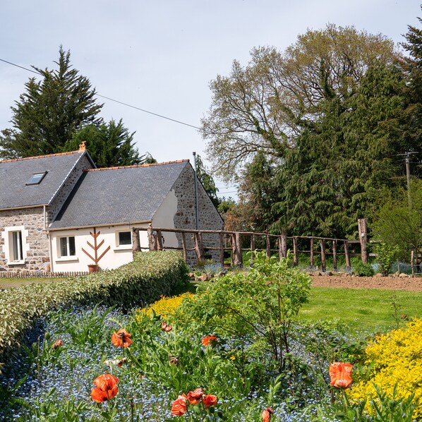 Cozy cottage nestled in a vibrant garden with a small window and a door, featuring a chimney.
