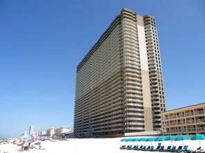 A tall hotel with multiple balconies, located near a beach with sun loungers and umbrellas. - Tidewater Beach Resort #1501 | Gulf Front + Breathtaking Views! (Panama City Beach)
