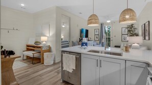 A modern kitchen with white cabinetry, a central island with a sink, and pendant lighting. - 1BR/1BA, Deck, Beach Access! + Free Attraction Tickets! (Santa Rosa Beach)