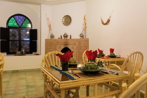 A dining area with a table set for four, chairs, a fireplace, and a stained glass window.