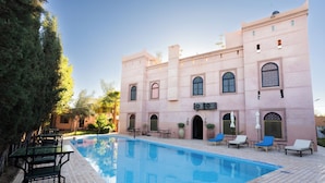 Zona de piscina amb gandules i un edifici amb finestres d'arc.