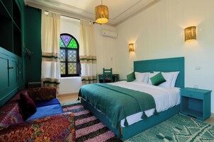 Un dormitorio con cama, mesita de noche, silla, ventana con cortinas y radiador.