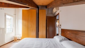 Ein Schlafzimmer mit einem hölzernen Bettgestell, einem Bett mit weißer Bettwäsche, einem Holzschrank und einem kleinen Nachttisch.