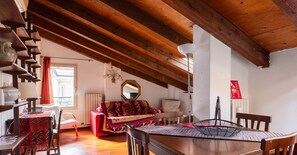 Um quarto aconchegante com teto de madeira, um sofá vermelho, uma mesa de jantar e uma cadeira.