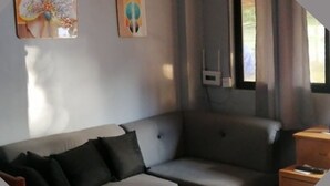 A modern living room with a grey sofa, a wooden side table, and abstract wall art. - Duplex beach house (Calabarzon)