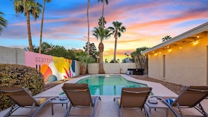 A pool area with lounge chairs, a colorful mural, and palm trees. - Desert Legacy | Scottsdale's Hidden Hideaway (Scottsdale)