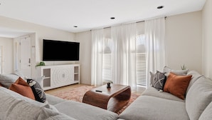 A modern living room with a flat-screen TV, grey sofas, and a wooden coffee table. - Desert Legacy | Scottsdale's Hidden Hideaway (Scottsdale)