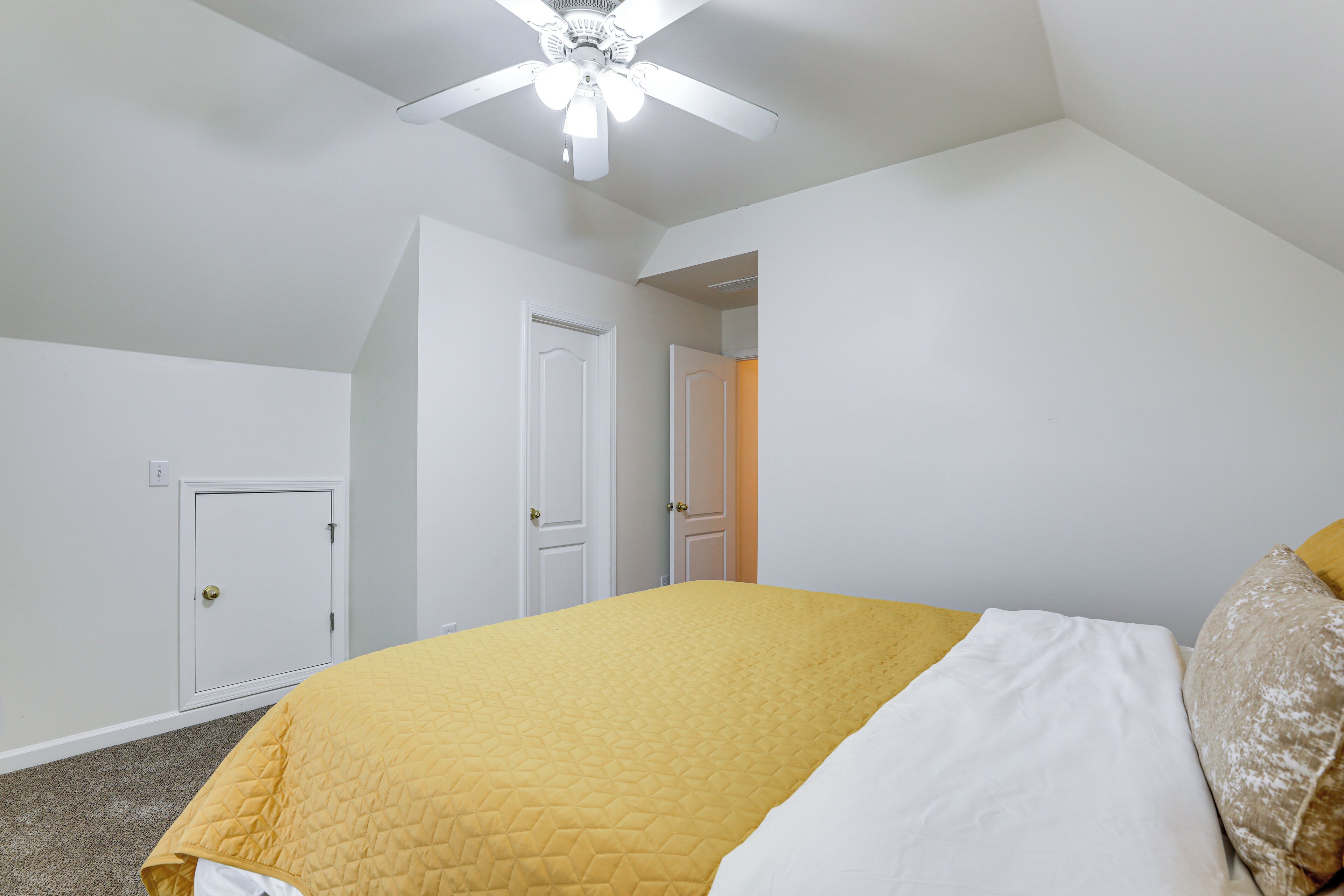 A bedroom with a bed, a ceiling fan, and white walls.