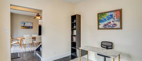 Um espaço de escritório moderno com uma mesa, cadeira, estante e um quadro na parede.