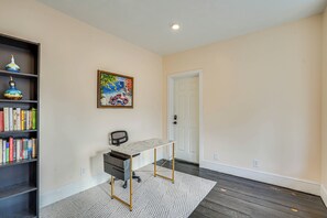 A room with a desk, bookshelf, and a door.