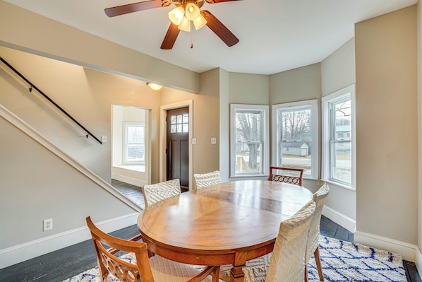 A dining area with a round wooden table, six chairs, and a ceiling fan.