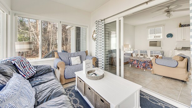 A spacious living area with a large window, a sofa set, a coffee table, and a sliding glass door leading to a kitchen. - Cozy Wells Cottage w/ Pool Access: 1 Mi to Beach! (Wells)