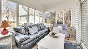 A sunlit room with a leather sofa, striped armchair, and a white table. - Cozy Wells Cottage w/ Pool Access: 1 Mi to Beach! (Wells)
