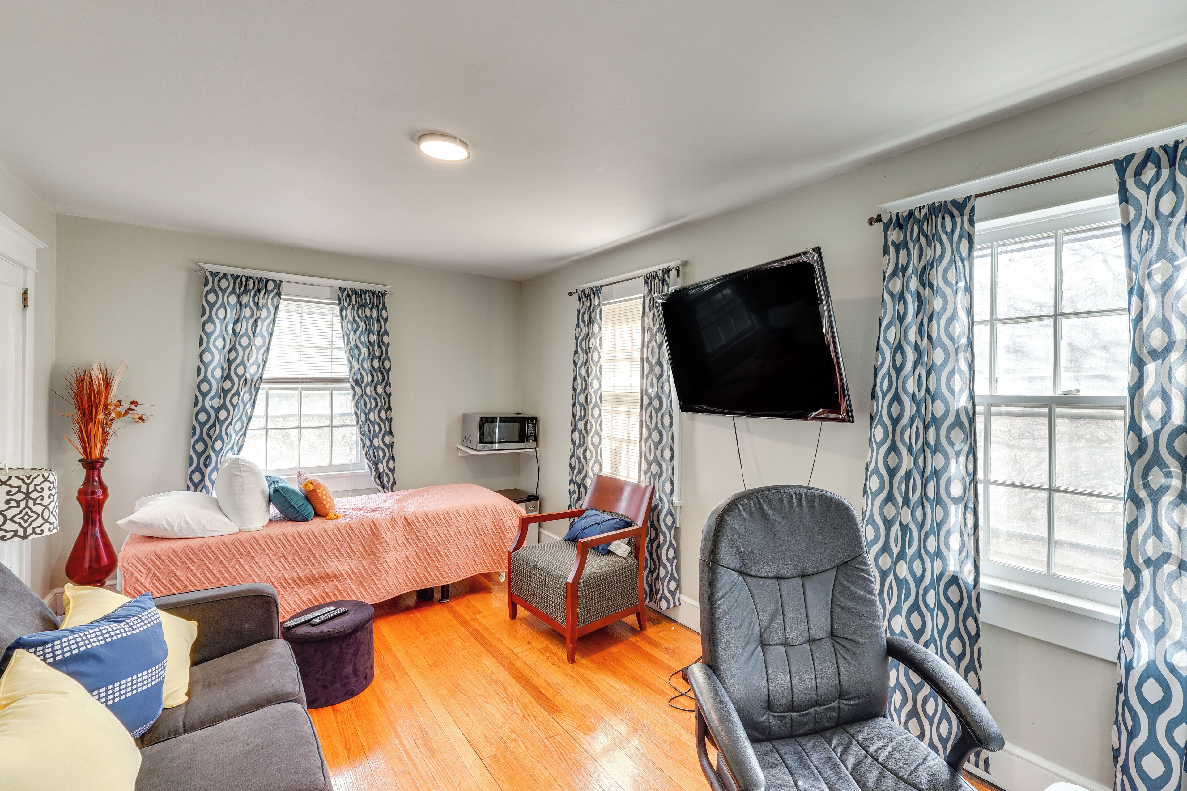 A room with a bed, a desk, a chair, a TV, and a window with curtains.