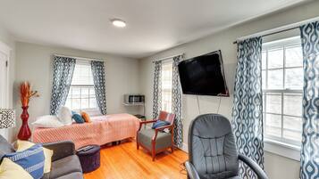 A room with a bed, a desk, a chair, a TV, and a window with curtains.
