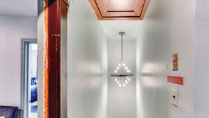 A hallway with a chandelier, a 'No Smoking' sign, and a door leading to a room with a bed. - Pet-friendly Ellenville Apartment in the Catskills (Ellenville)
