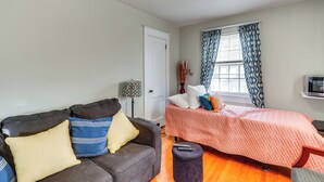 A bedroom with a bed, a sofa, a lamp, and a TV. - Pet-friendly Ellenville Apartment in the Catskills (Ellenville)