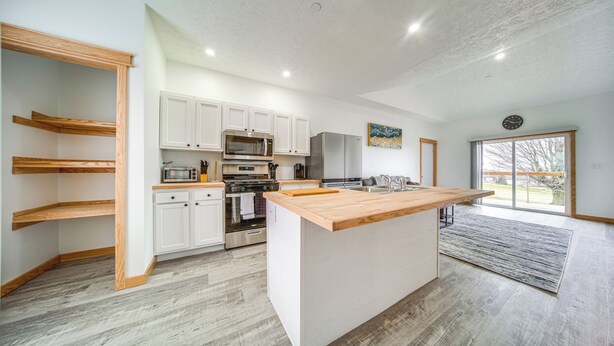 A modern kitchen with white cabinets, stainless steel appliances, and a wooden island. - Balcony+ Golf Course View: Quiet Erie Getaway (Erie)