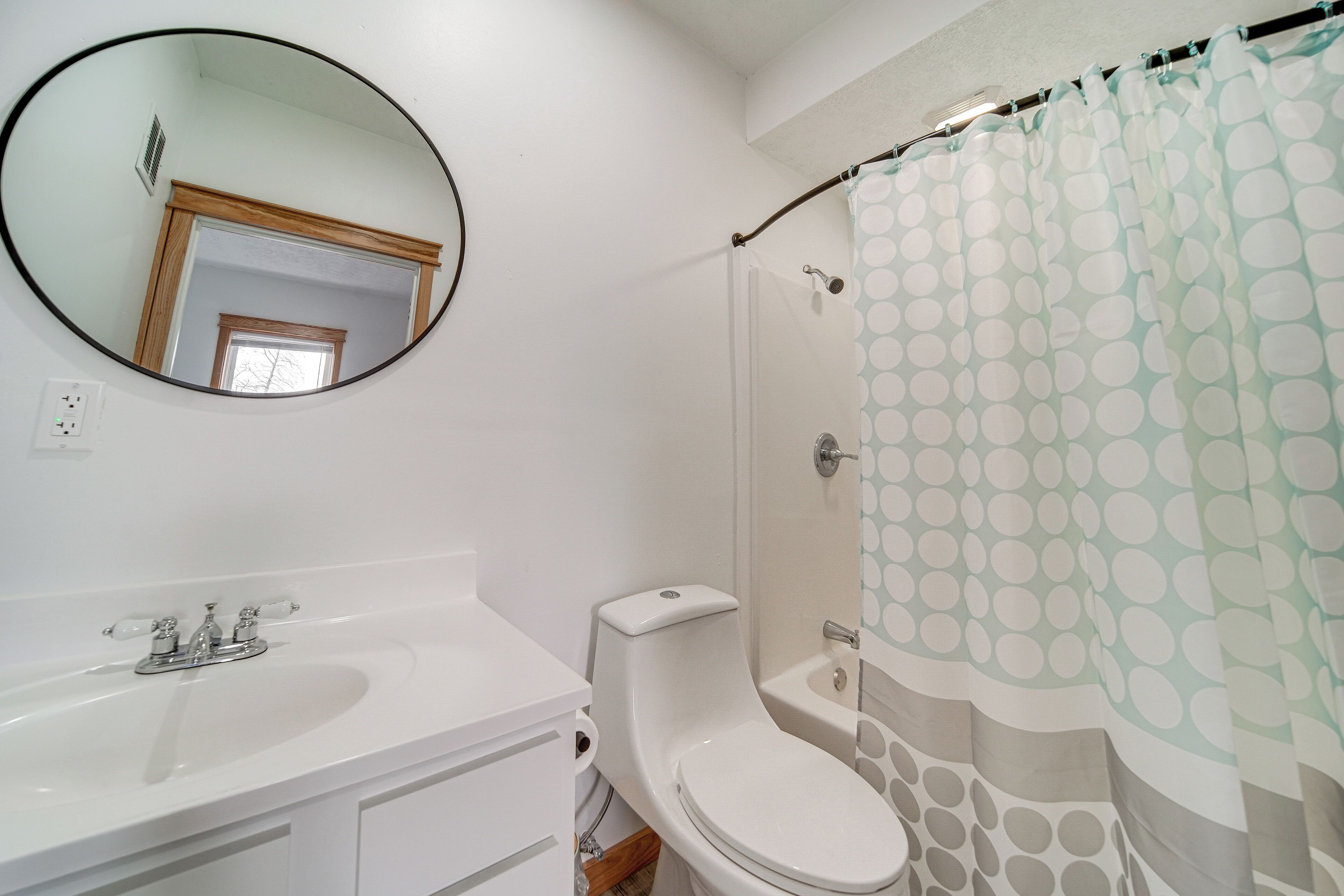 A bathroom with a white sink, toilet, and shower curtain with a polka dot pattern.