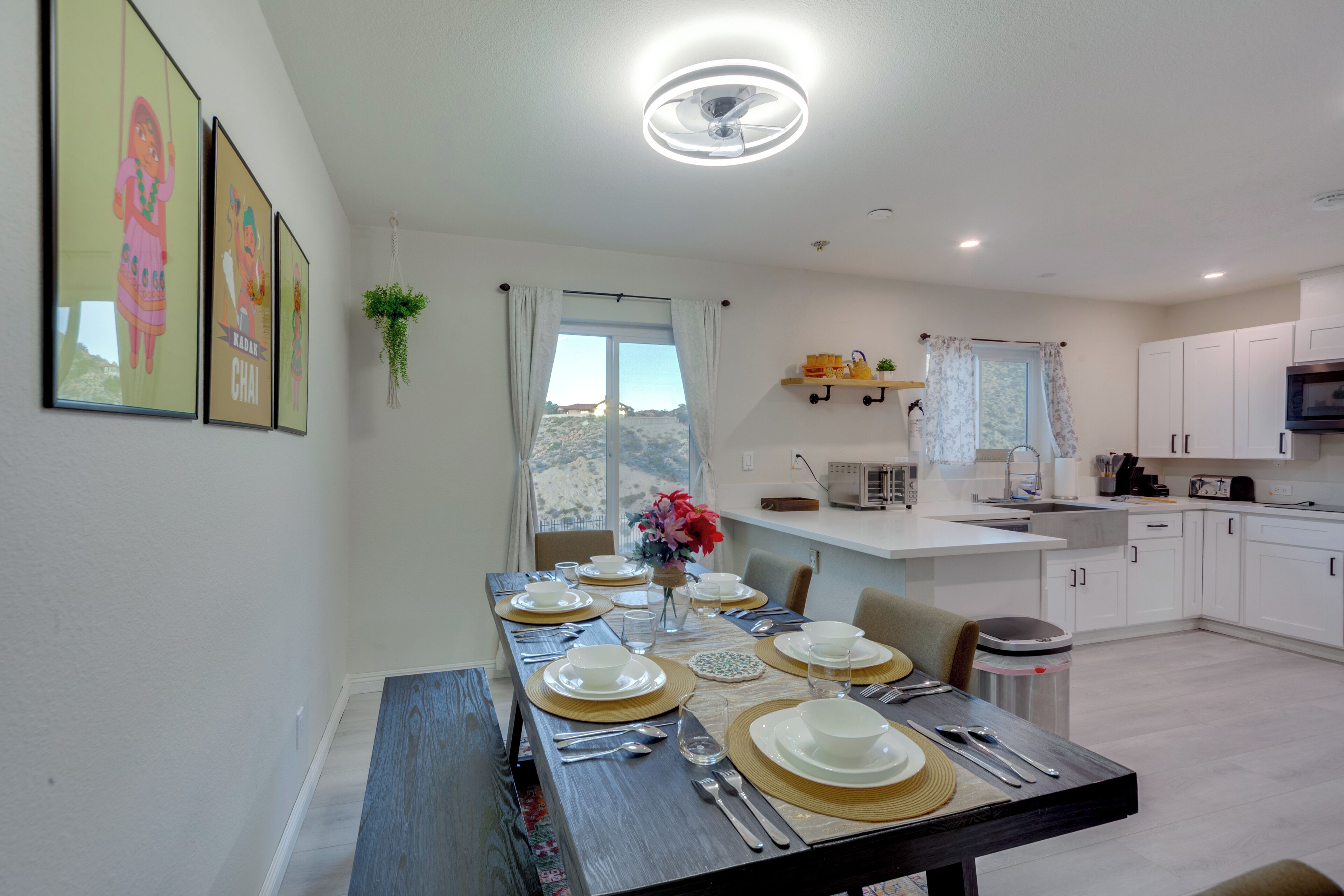 A modern kitchen with white cabinets, a microwave, and a dining area set for a meal.