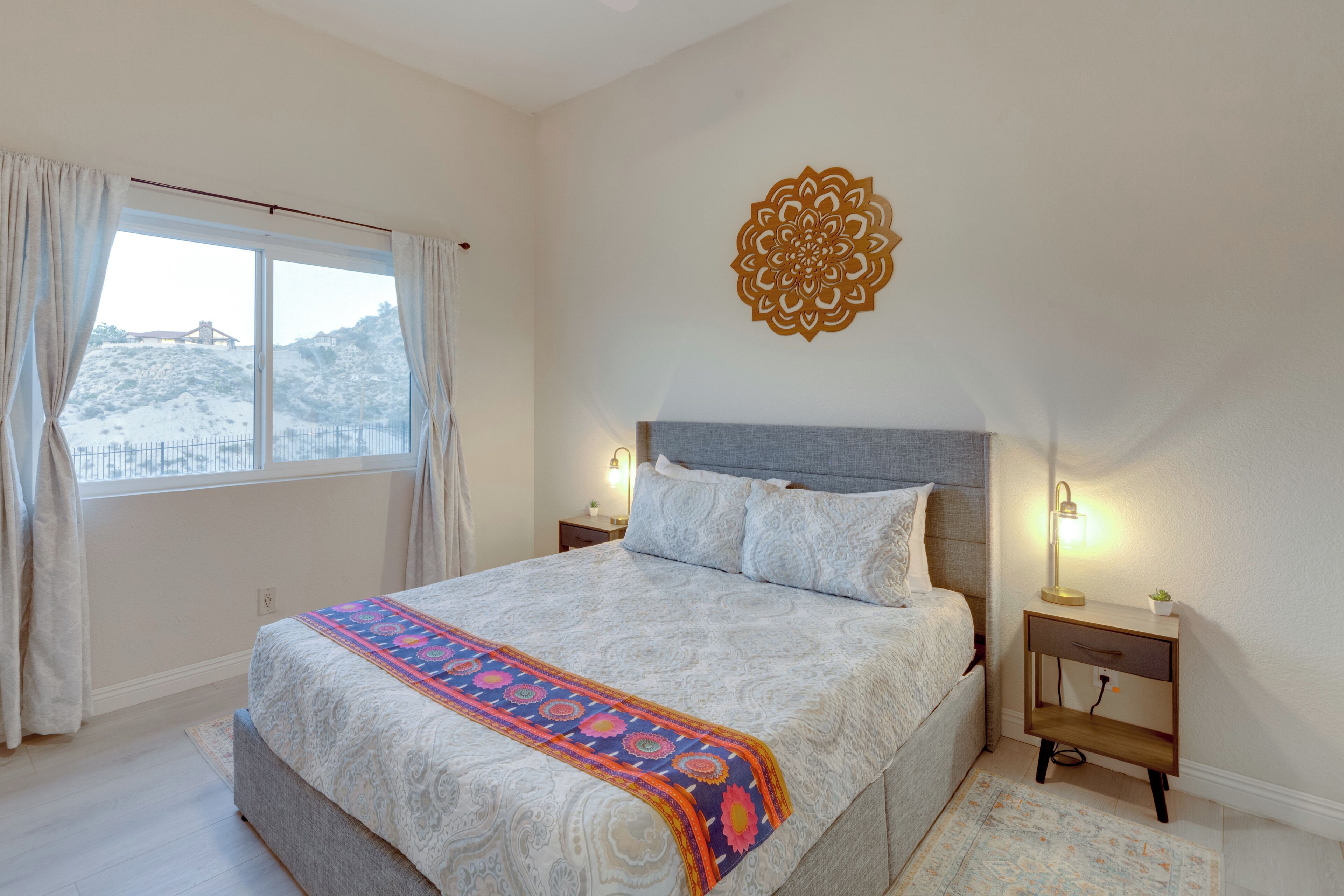 Een slaapkamer met een groot bed, een decoratief kunstwerk aan de muur en een nachtkastje met een lamp.
