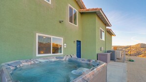 Een hottub voor een gebouw met een groene gevel, een blauwe deur en een heldere lucht op de achtergrond.