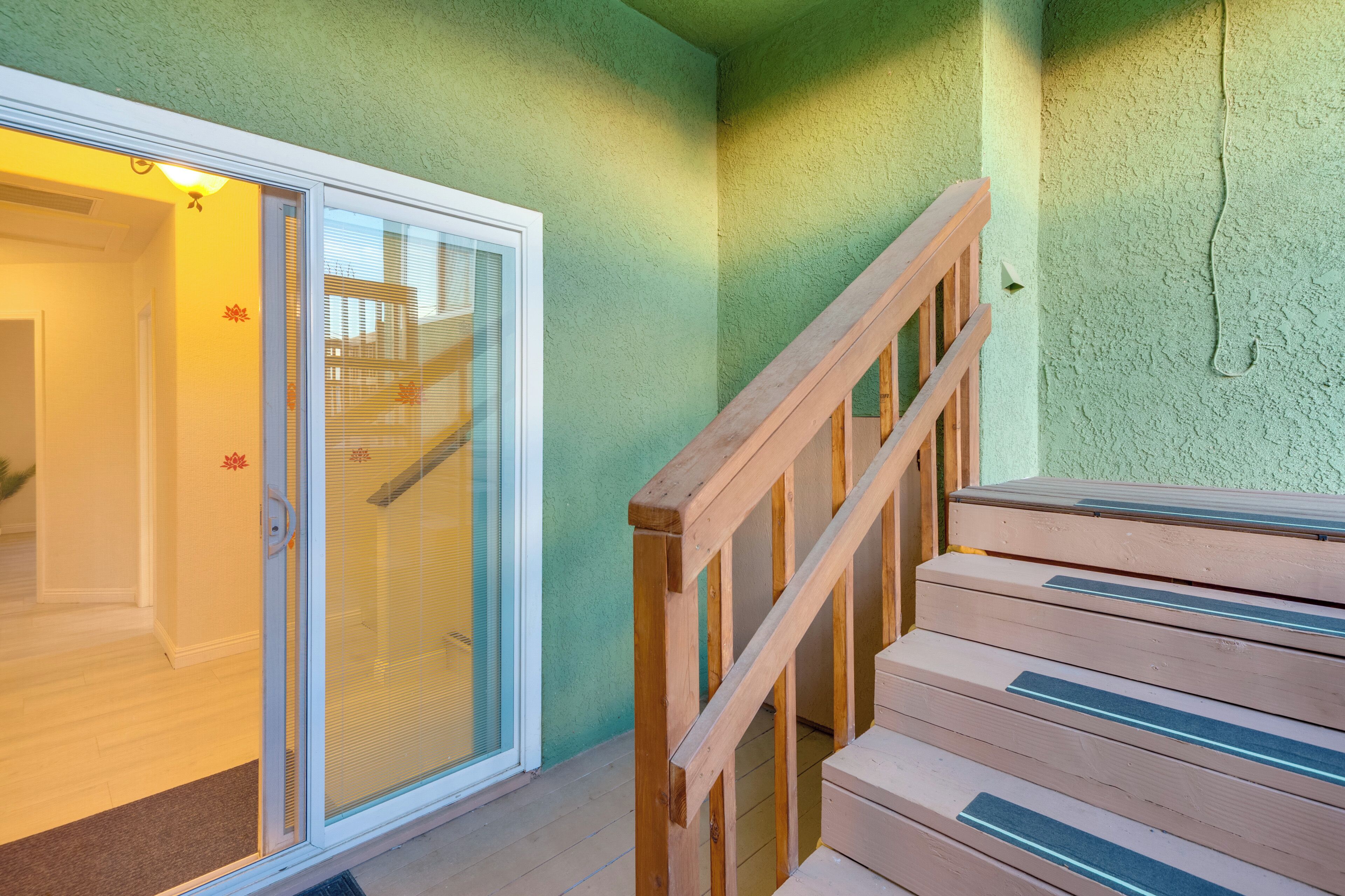 A staircase with wooden railings leading to a glass door entrance.