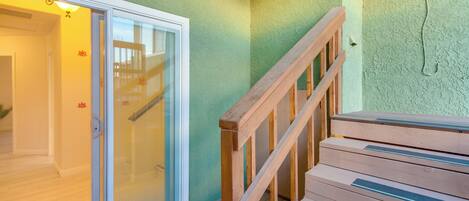 A staircase with wooden railings leading to a glass door entrance.