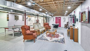Una habitación amplia con mesa de ping-pong, asientos cómodos y dardos.