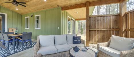 A cozy, well-lit wooden cabin with a dining area, sofa, and wicker chairs.