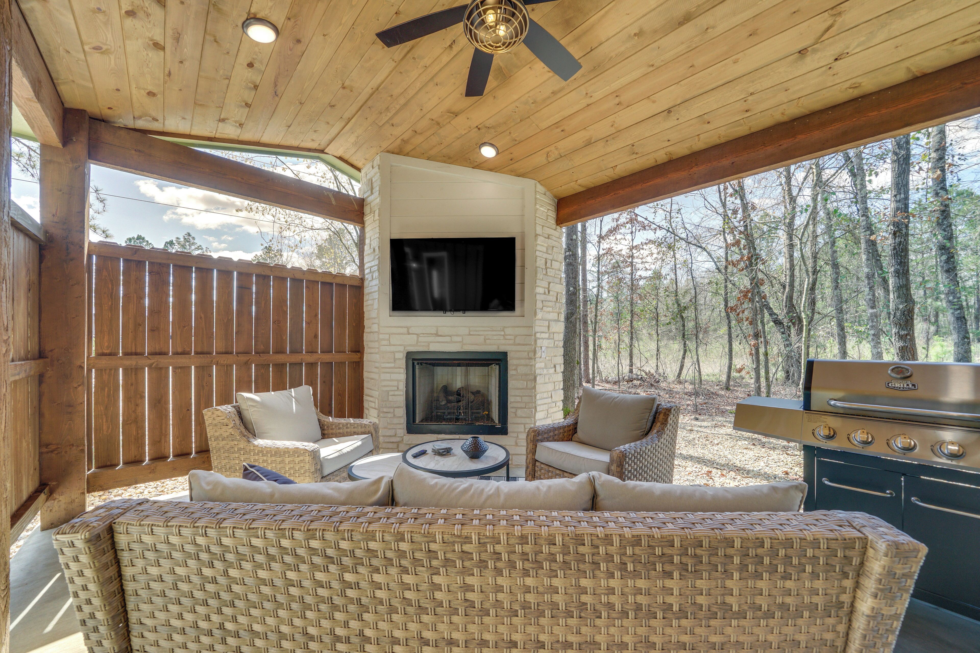 An outdoor patio with wicker furniture, a stone fireplace, and a grill.
