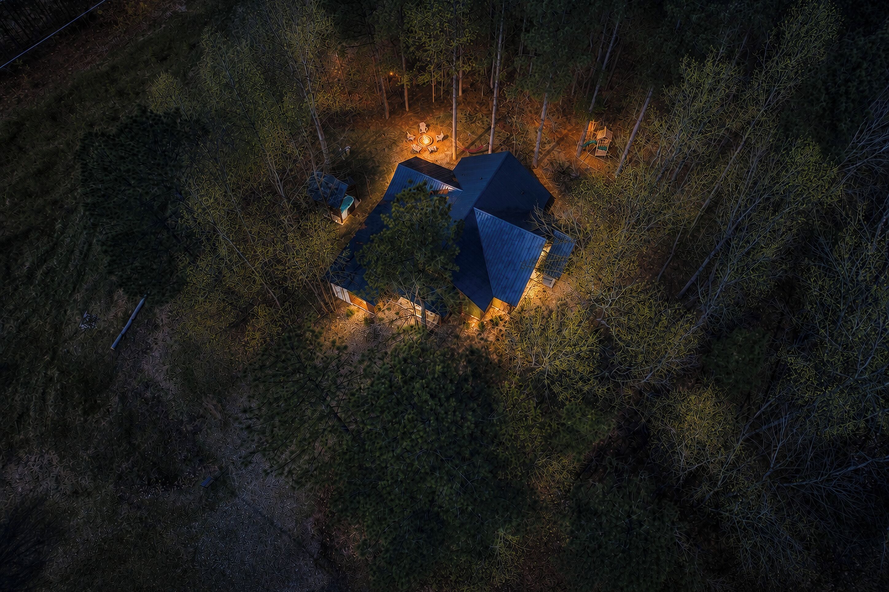 A remote cabin surrounded by dense forest, with a clear night sky.