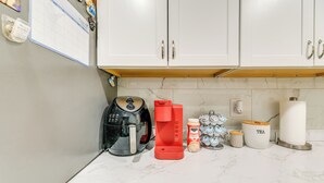 A kitchen with white cabinets, a coffee maker, a kettle, and tea storage.