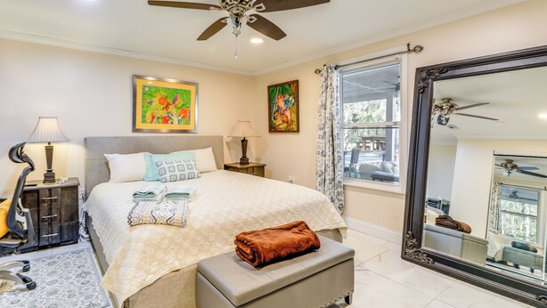 A well-lit bedroom with a bed, bedside lamps, a ceiling fan, and a large mirror.